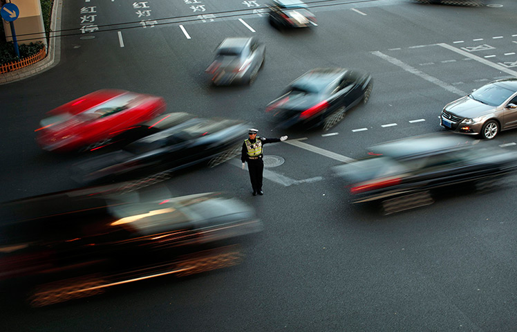 24 hours: Shanghai, China: A policeman directs traffic in a busy street