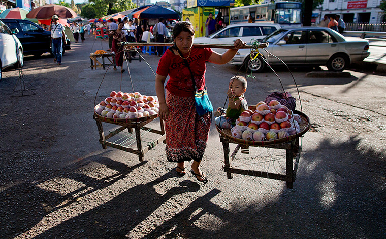 24 hours in pictures: A street vendor carries apple with her child 