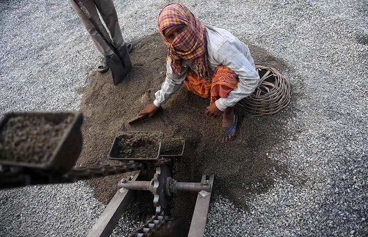 24 hours: Indian labourers work on material to construct a road