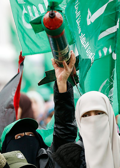 Hamas: A Palestinian woman holds a model of the Qassam rocket