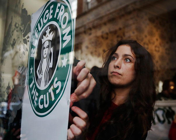 Starbucks: A demonstrator sticks up a protest poster in the window of a Starbucks 