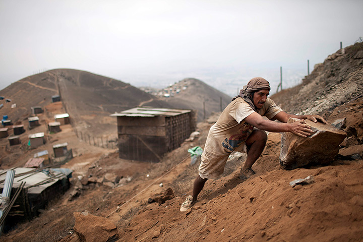 24 hours: Lima, Peru: A man moves a rock as he builds a shack on a mountain top