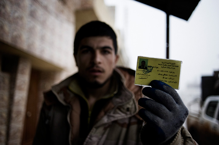 Al-Qusayr Syria: A Syrian Army defector holds up his military ID 