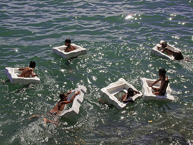 In pictures: splash: Children play with polystyrene in the sea off East Timor
