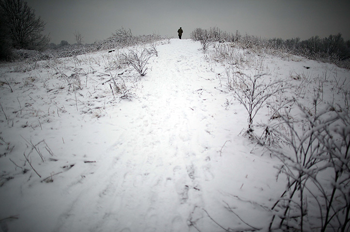 Snow:  A man walks up a snow covered hill on Wimbledon common