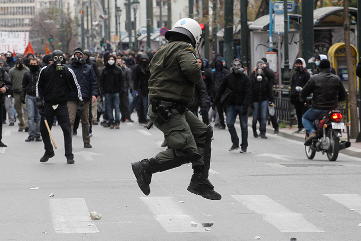 Greece protests: A riot policeman tries to avoid a stone thrown by a protester