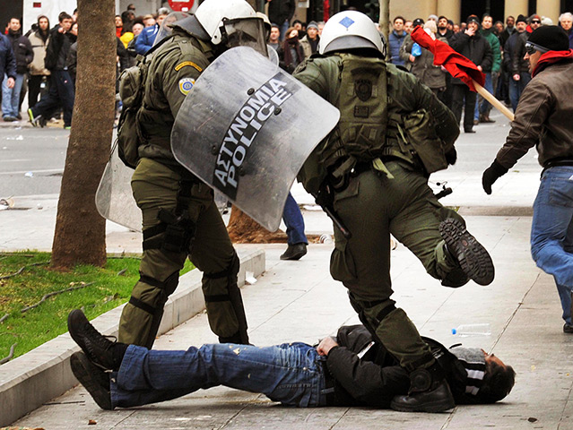 Greece protests: A riot policeman kicks an anti-austerity protester