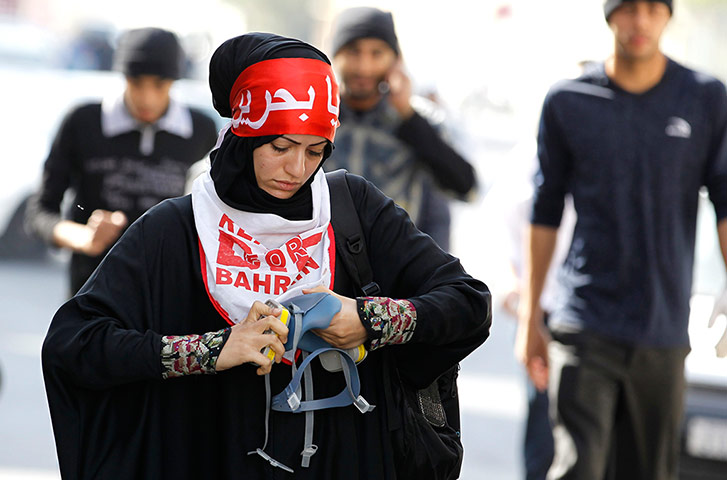 Bahrain: An anti-government protester fixes her tear gas mask