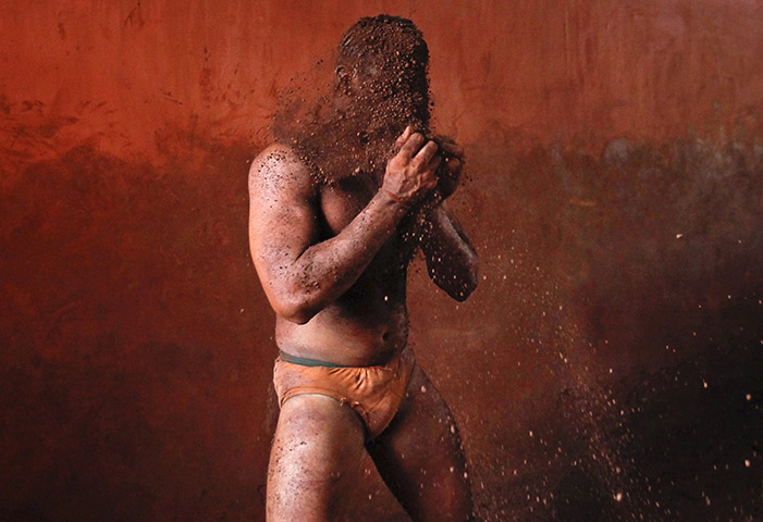 24 hours: Kolhapur, India: A wrestler rubs his hands with mud 