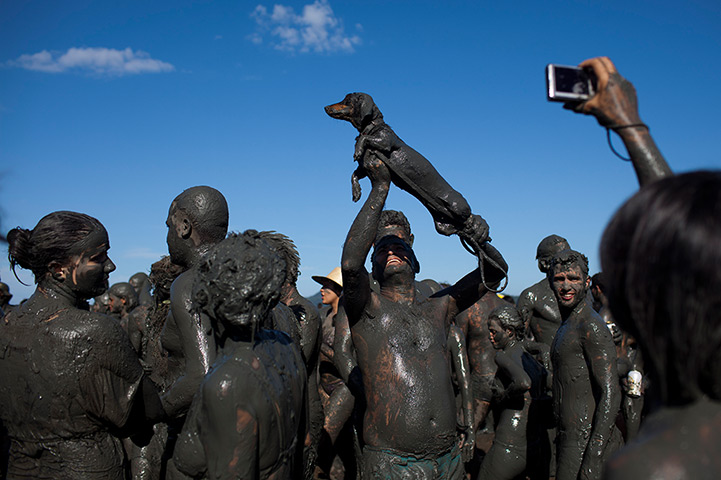24 hours: Parati, Brazil: A man holds up his mud-covered dog at the Mud Block parade