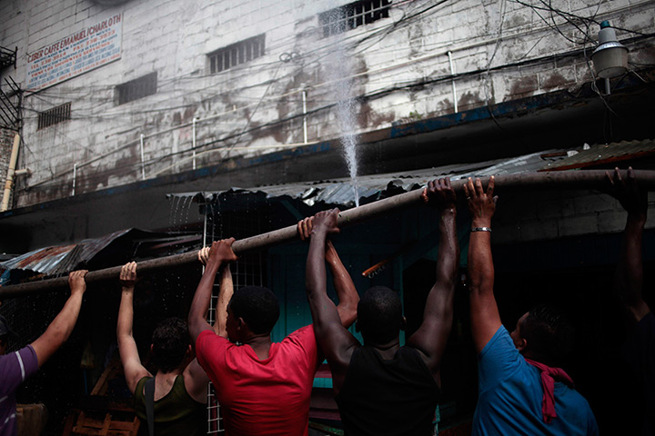 24 hours: Tegucigalpa, Honduras: Workers in Comayaguela market carry a fire hose