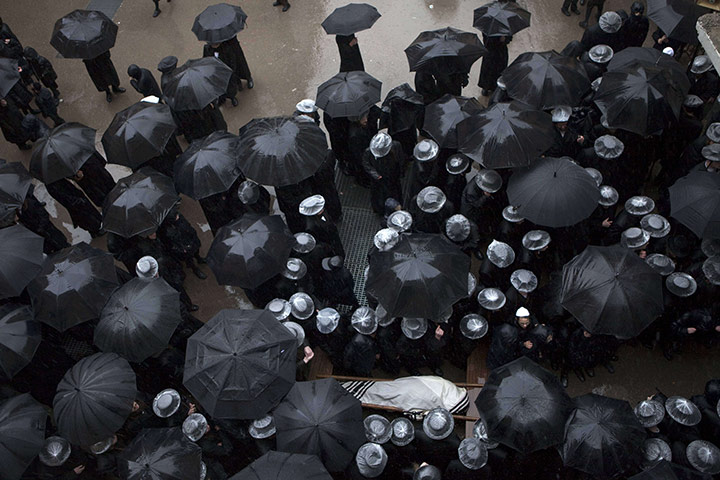 24 hours in pictures: Jerusalem: Ultra Orthodox Jews hold umbrellas and cover their hats
