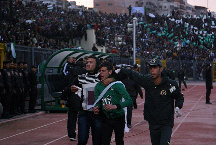 Port Said clashes: A wounded Egyptian fan of Al-Masry is escorted by a medic