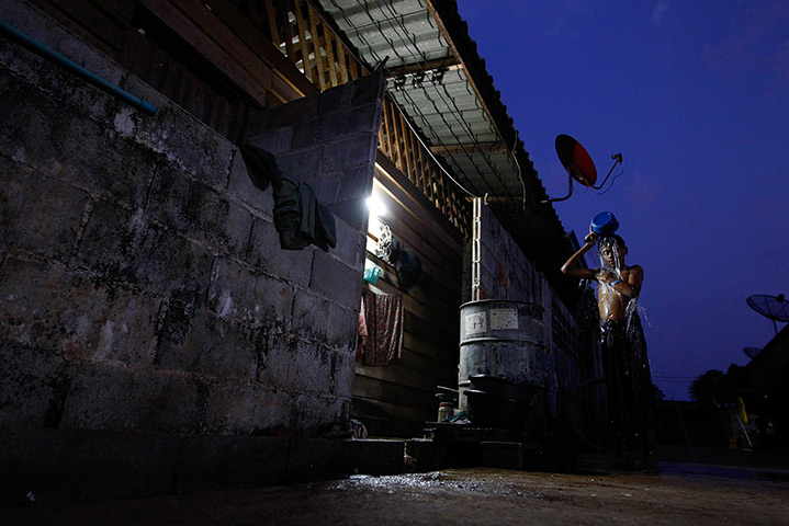 24 hours in pictures: A boy washes himself after working in Sangkhlaburi