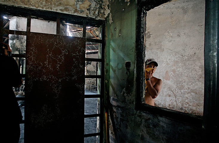 24 Hours: A prisoner looks through a window burnt after rioting in the Kerobokan jail