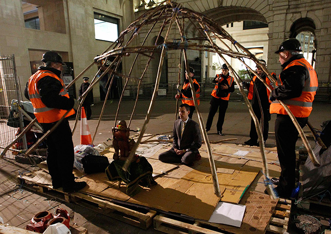 Occupy London eviction: A protester meditates as bailiffs lift the frame of his tent