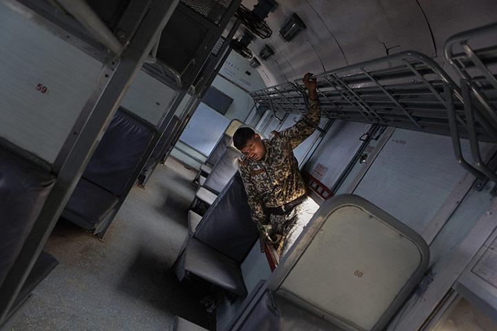 24 hours in pictures: An Indian disaster response worker searches a rail car 
