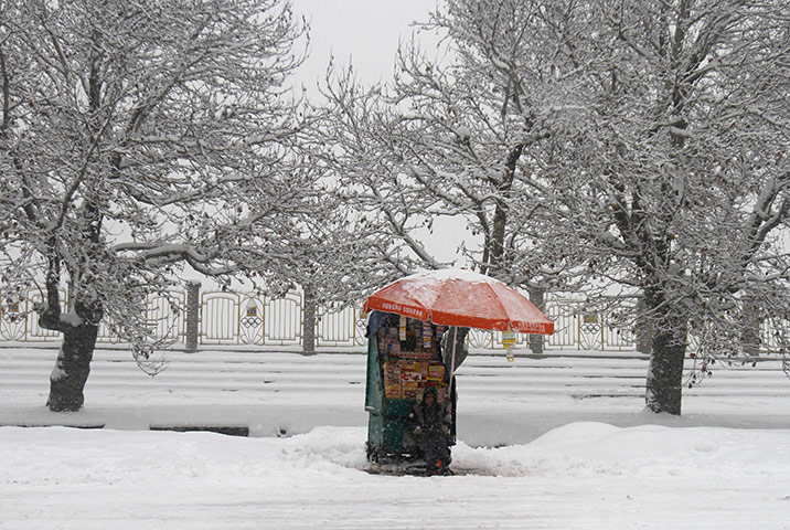 24 hours in pictures: An Afghan vendor waits for customers during a snowstorm