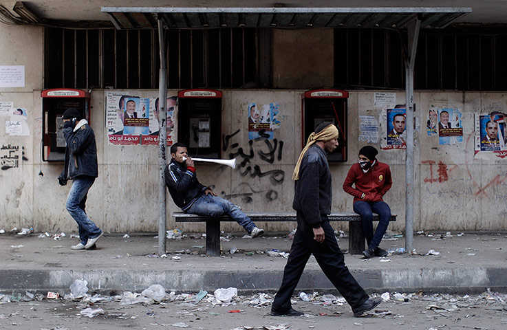 Egypt Protests: An Egyptian protestor sitting in a bus stop blows a vuvuzela