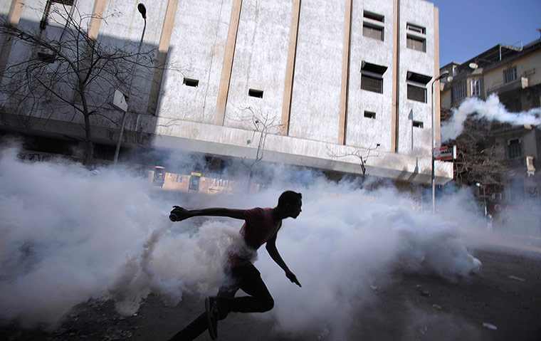 Egypt Protests: An Egyptian protestor throws back a tear gas canister