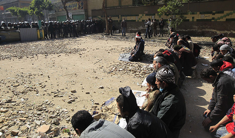 Egypt Protests: Egyptian riot policemen stand guard as protesters perform their prayers