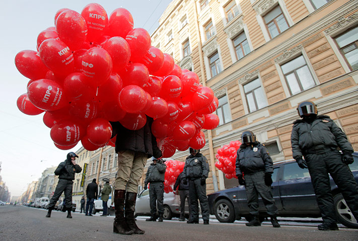 Russia Protest: A protester holding red balloons walks past riot policemen in St Petersburg