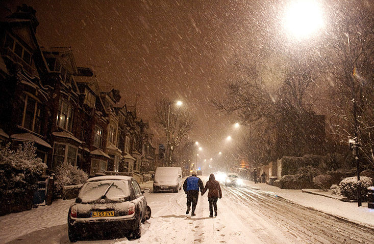 UK snow: A couple walk up Muswell Hill, north London as cars struggle in the snow