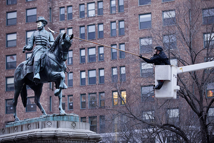 24 hours: Washington, DC, USA: A US Park Police officer removes a mask from a statue