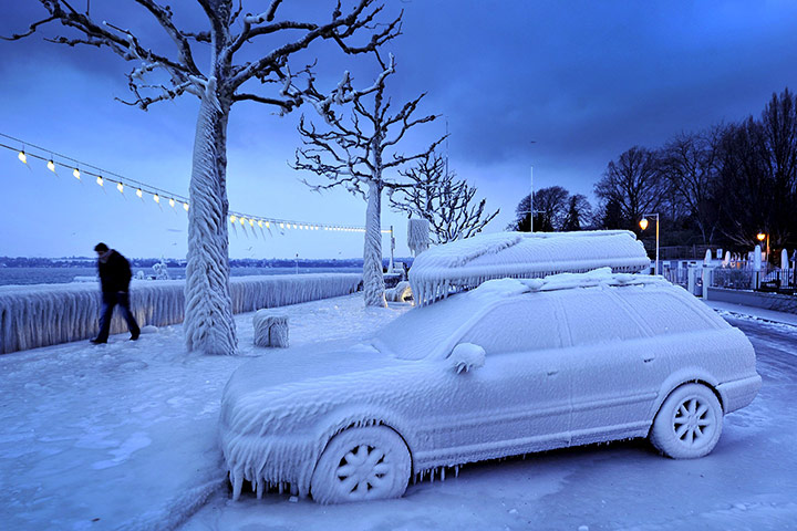24 hours: Versoix, Switzerland: A man walks past an ice-covered car at Lake Geneva 