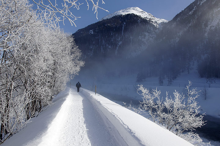 Europe weather: A pedestrian walks along the Inn river in Grisons, Switzerland