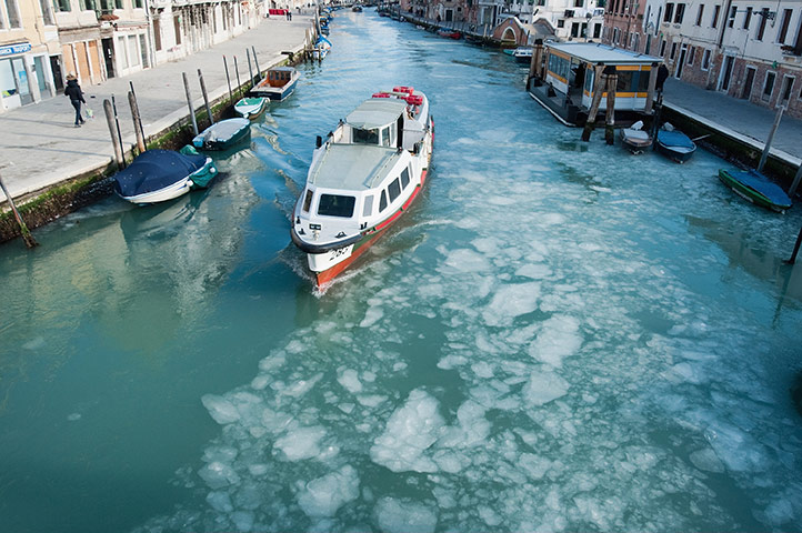 Europe weather: A waterbus sails on frozen Canal of Cannaregio in Venice, Italy