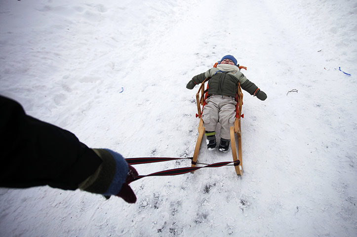 Europe weather: A child lies on a sled while his father walks on a street in Sarajevo 
