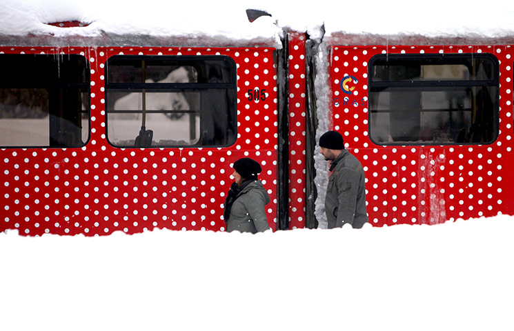 Europe weather: A couple walks near tramcars in heavy snowfall in Sarajevo