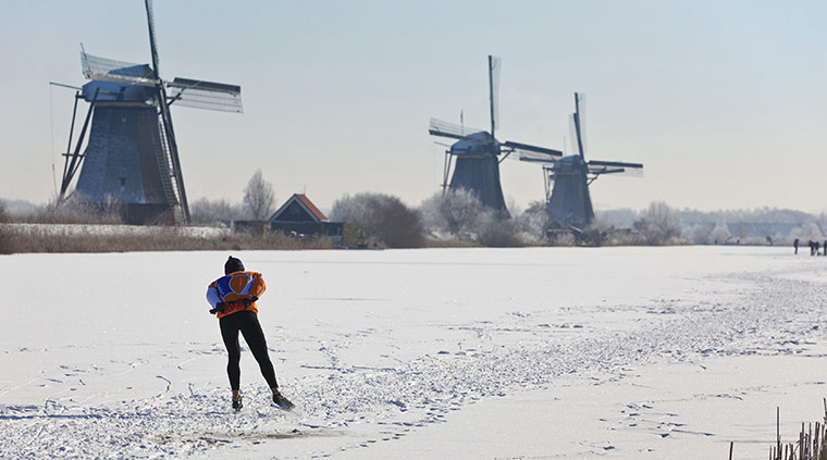 Europe weather: A skater past three windmills on natural ice in Kinderdijk, The Netherlands