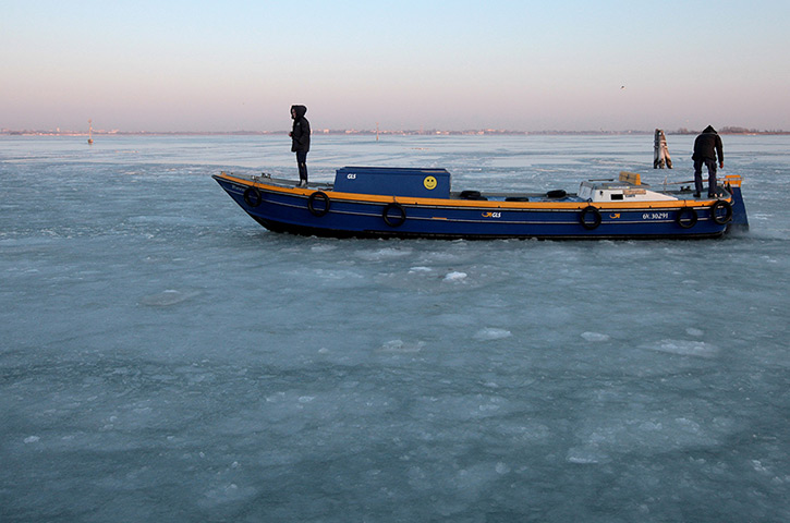 Frozen Venice: People stand on a boat on the frozen Lagoon