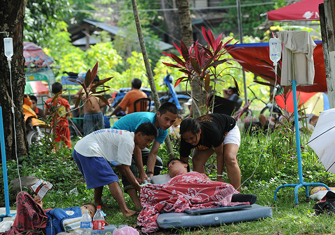 Philippines earthquake: Relatives arrange a patient's improvised bed resting under a tree