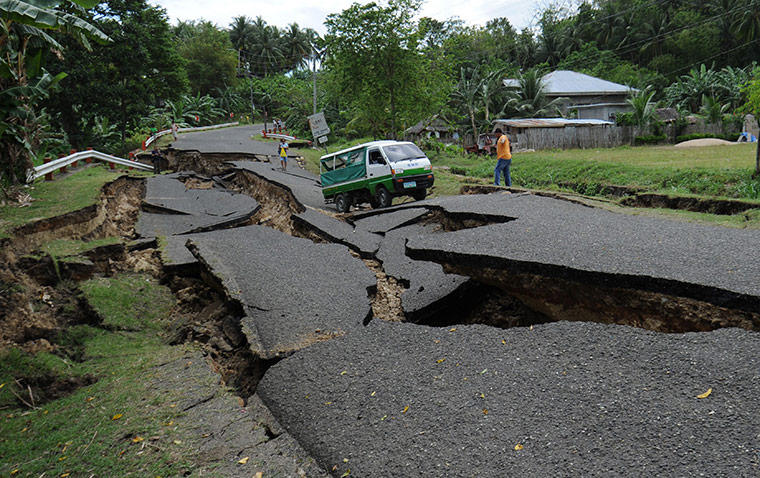 Philippines earthquake: A vehicle carrying the body of a victim manoeuvres through a damaged road