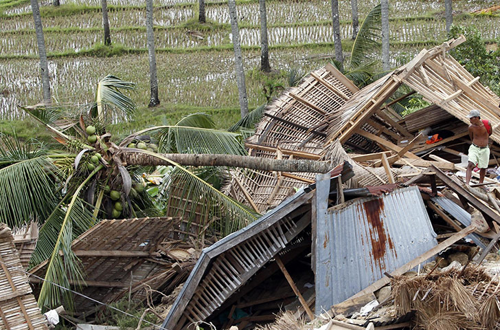 Philippines earthquake: A man stands on top of the houses destroyed by a landslide