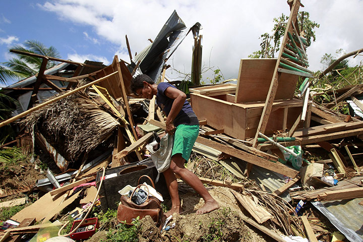 Philippines earthquake: A woman retrieves belongings from the rubble of her house