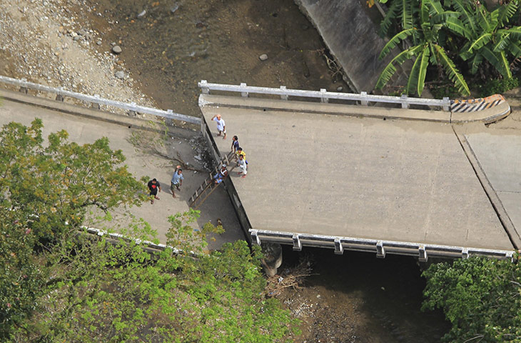 Philippines earthquake: Residents improvise with ladders to cross a damaged bridge in Tayasan town