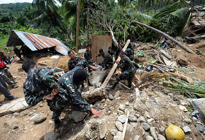 Philippines earthquake: Philippine soldiers remove stones from a destroyed house