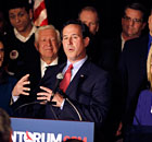 Rick Santorum addresses supporters last night. A smiling Foster Friess stands just behind him.