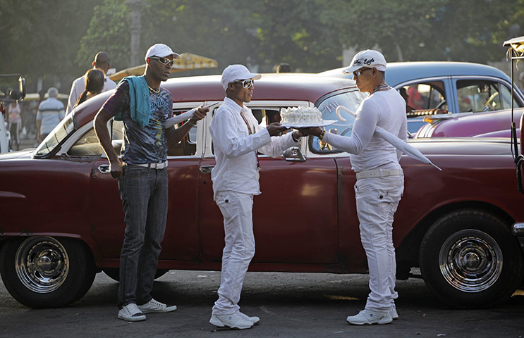 24 hours in pictures: Men carry a cake beside a taxi in Havana 
