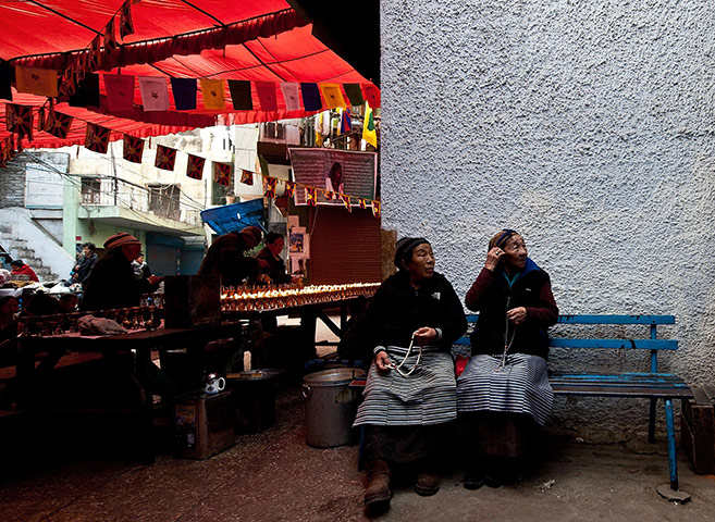 24 hours in pictures: Elderly Tibetan women sit outside a Buddhist temple