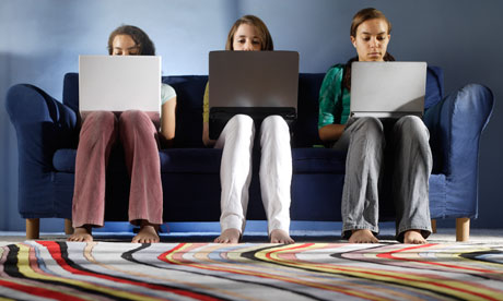 Teenage girls using laptops on sofa in living room