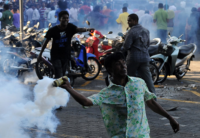 Maldives unrest: An anti-government protester throws back a teargas cannister at police 