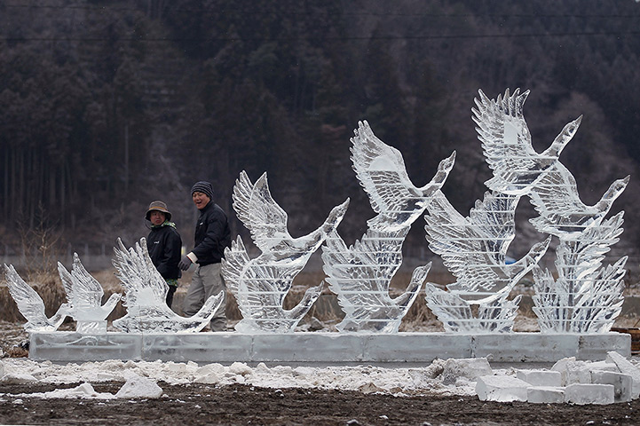 Japan anniversary: Two men walk past an ice sculpture in Rikuzentakata, Japan