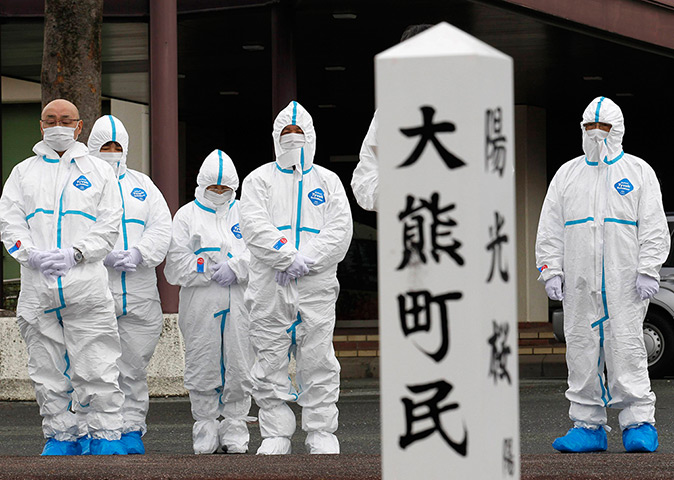 Japan anniversary: Evacuees of Okuma town, dressed in protective suits, offer prayers