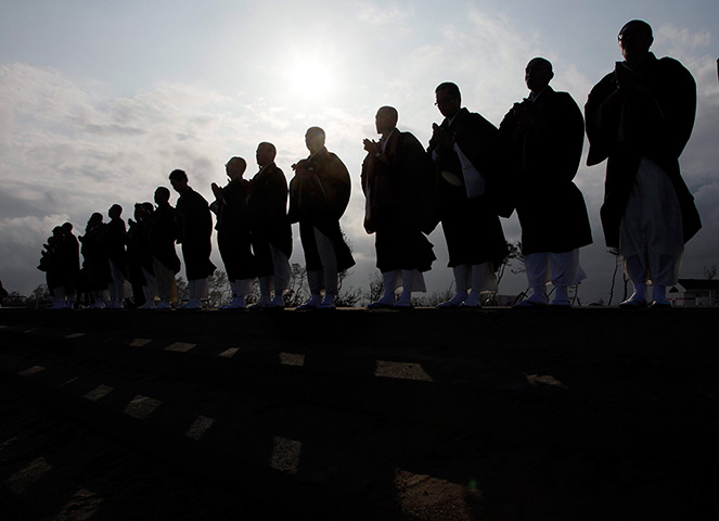 Japan anniversary: Bhuddhist monks form a line on the water's edge