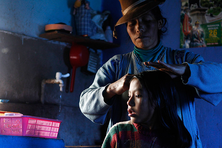 24 hours: Langui, Peru: A woman combs her daughter's hair in their house